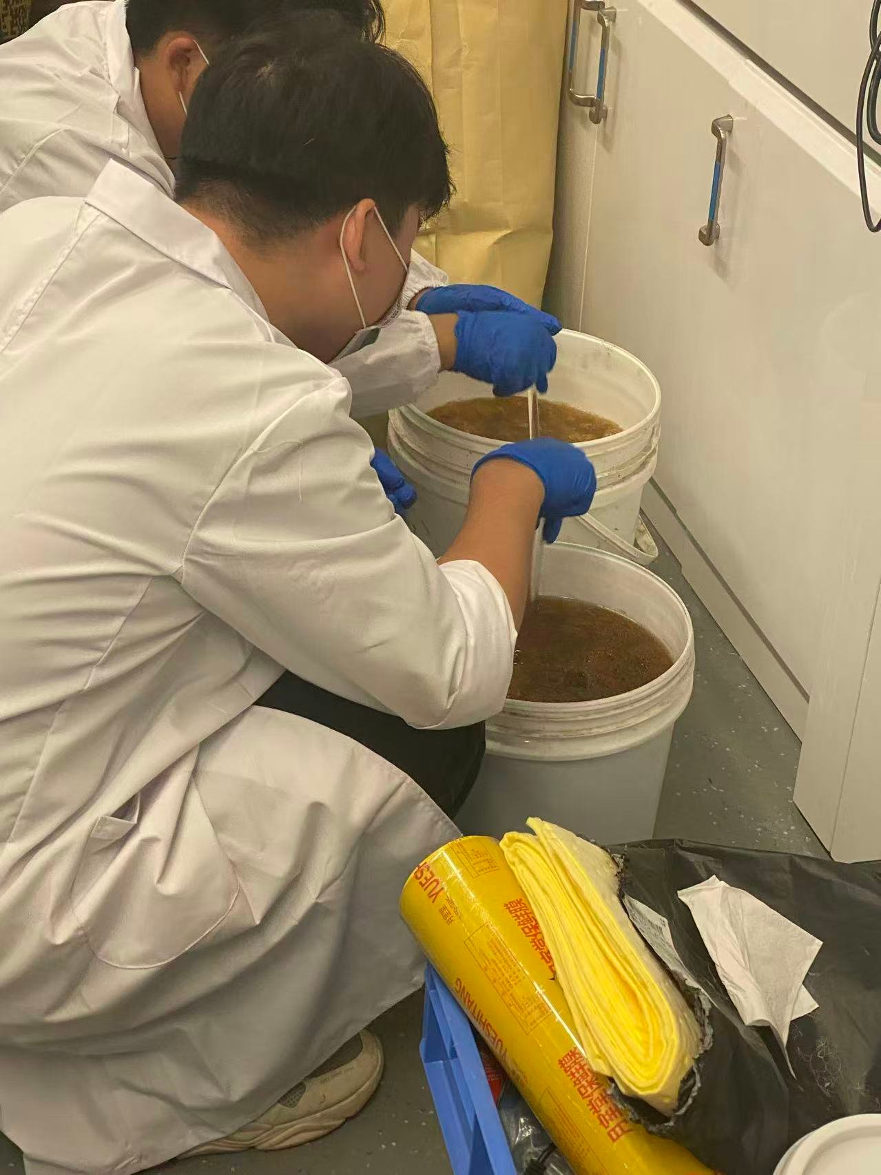 Researchers mixing material batches in laboratory containers