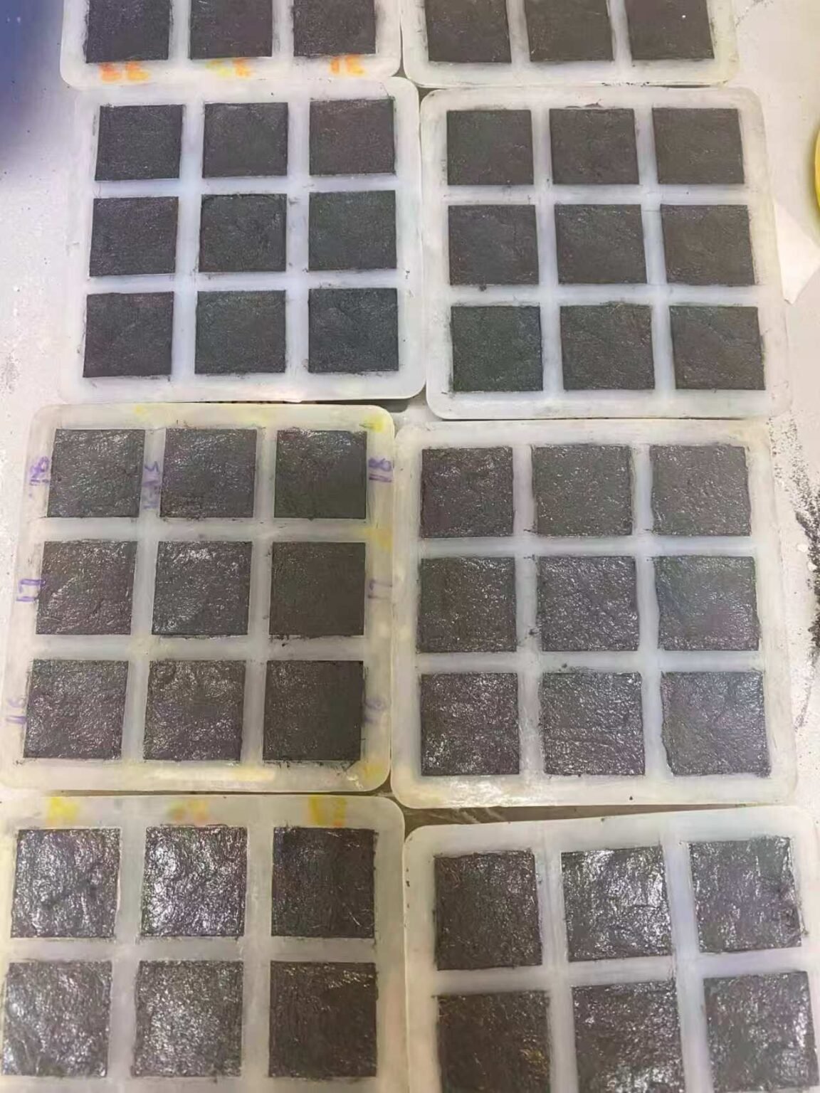 Laboratory-scale cementitious test specimens prepared in square molds for experimental evaluation.